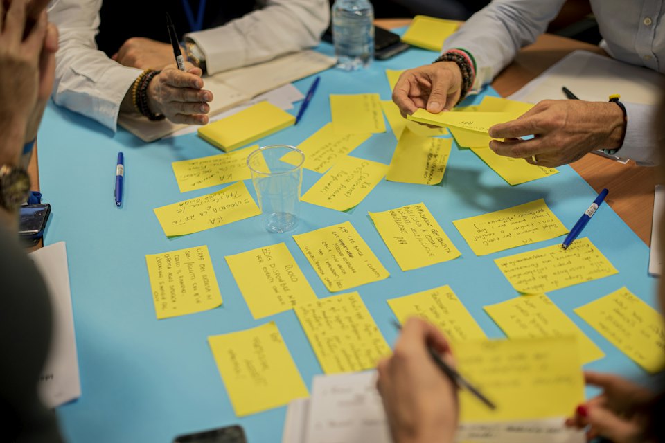 Des mains écrivent sur des post-it jaunes, pendant un atelier