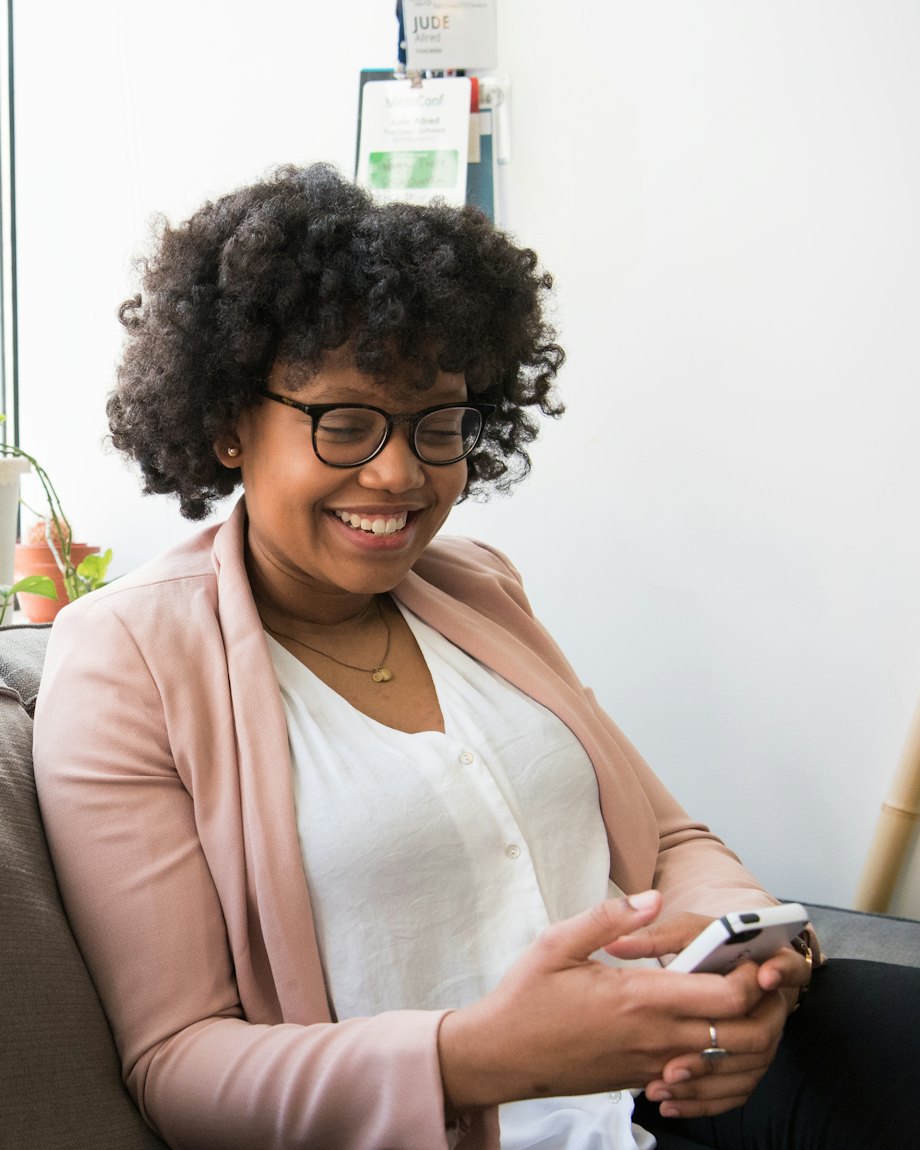 Une collaboratrice souriante écrit sur son téléphone